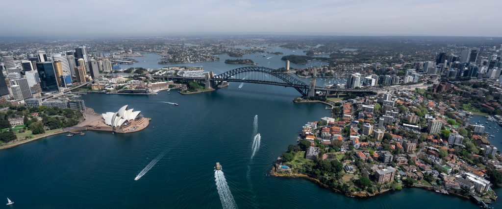 Stunning aerial view capturing Sydney Opera House and Harbour Bridge in daylight.